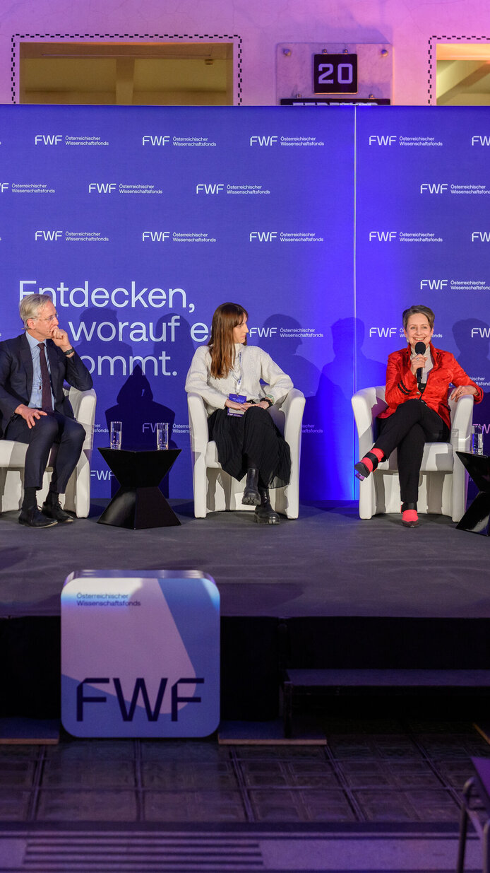 Personen in Sesseln sitzend auf dem Podium