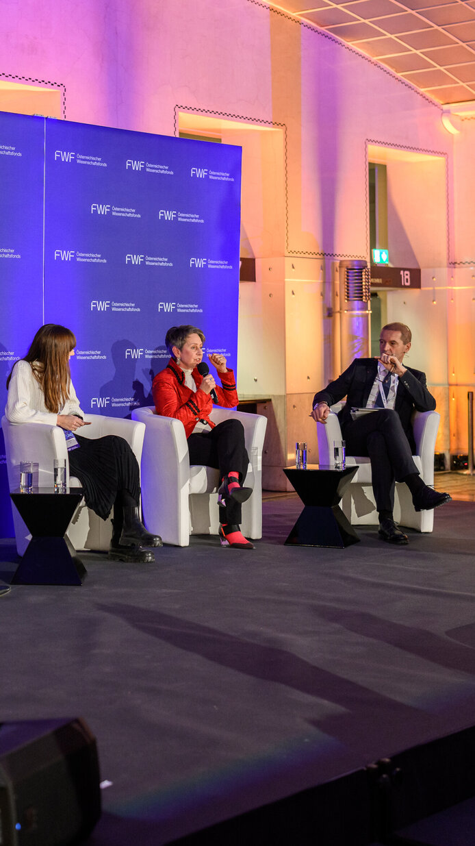 Personen in Sesseln sitzend auf dem Podium