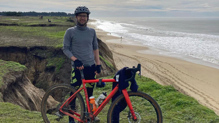 Junger Mann in Sportoutfit und mit Mountainbike am Strand