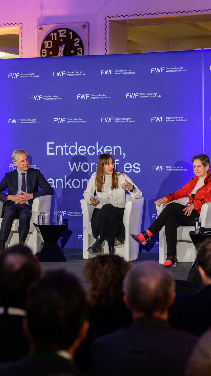 Personen in Sesseln sitzend auf dem Podium