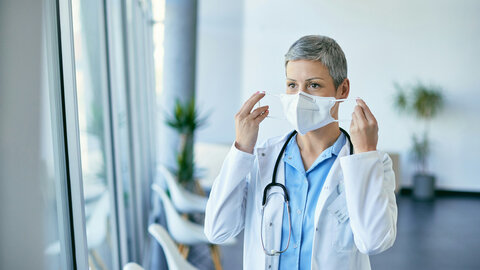 Female doctor in hospital puts on a mask