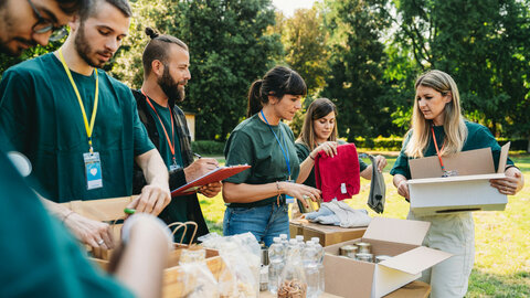 Six young volunteers sort food outdoors.