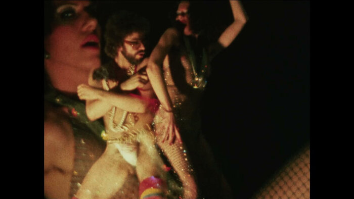 Filmstill aus der queeren Community zeigt zwei Frauen und einen Mann in lasziven Posen und Kostümen.